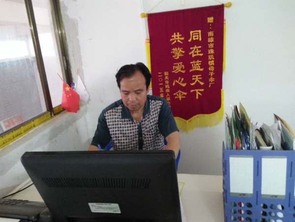 图为是“新型母子伞”和“一种子母伞”的发明人，南雄市残疾人刘明同志在办公中。