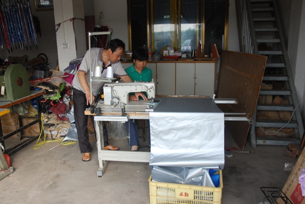 图为是“新型母子伞”和“一种子母伞”的发明人，刘明同志在悉心指导新来的员工如何进行操作电动拉布机。