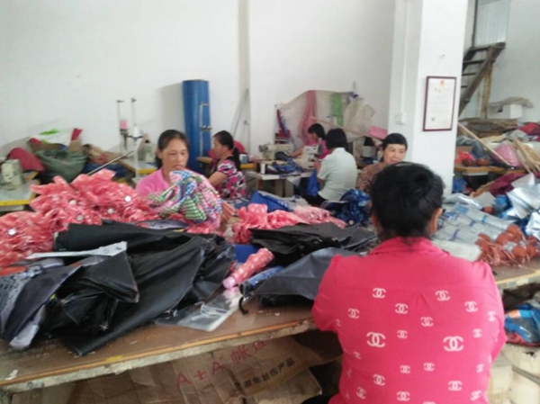 图为是南雄市残疾人刘明开办的珠玑镇“母子伞厂”的员工，在紧张的进行打顶、扣尾珠、合片及扣带的劳动中。