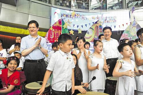 图为广东省委常委、常务副省长徐少华和广州市市长陈建华在孩子们中间欣赏表演