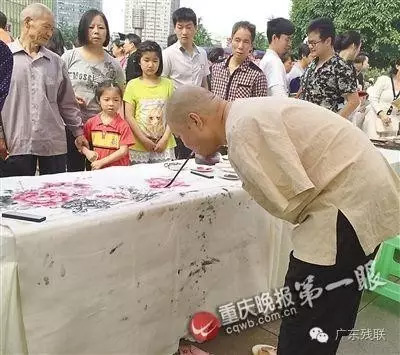 图为残疾画家用嘴衔笔作画