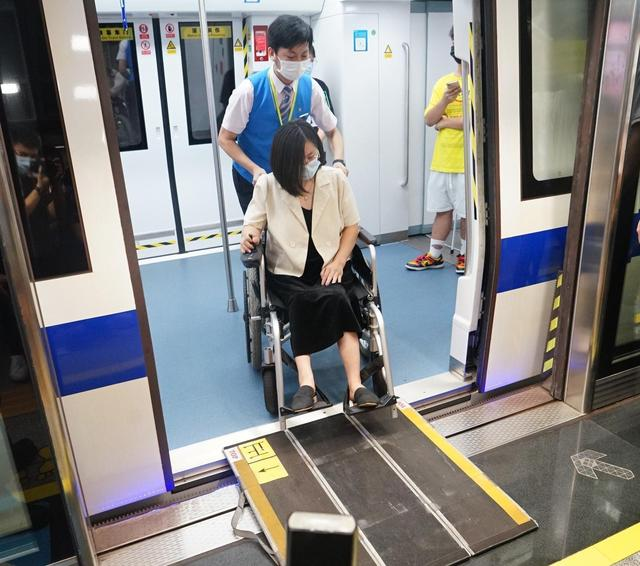 志愿者帮助残障人士进地铁。