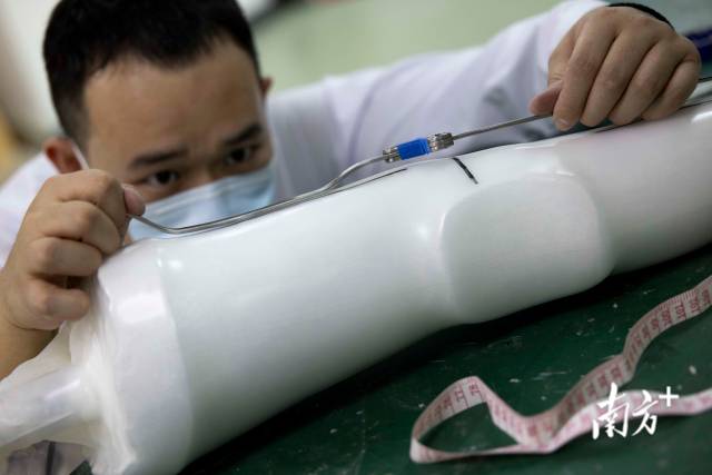 矫形器技师张志远用手工制作出矫形器大小腿连接处的枝条，并来回不断打磨调试。